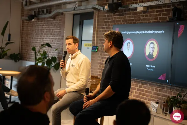 Koen Stam of Personio Netherlands seated on stage with the 'Learnings growing Lepaya — developing people' slide behind him at SaaStock Local Amsterdam Q2 2024