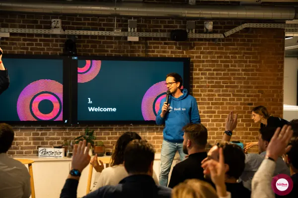 Joran Hofman opening SaaStock Local Amsterdam Q2 2024 in his Reditus hoodie, audience hands raised under a '1. Welcome' slide